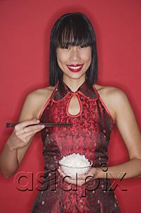 AsiaPix - Woman against red background, dressed in cheongsam, holding bowl of rice