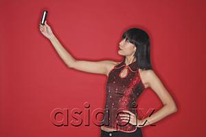 AsiaPix - Woman using mobile phone to take a picture of herself, hand on hip