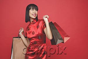 AsiaPix - Woman in red cheongsam, carrying shopping bags, looking away