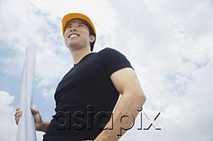 AsiaPix - Young man in hardhat, carrying blueprints, smiling