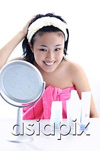 AsiaPix - Young woman sitting at dressing table, looking in mirror