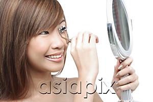 AsiaPix - Teenage girl using eyelash curler, looking in mirror