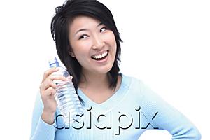 AsiaPix - Young woman holding bottle of water, looking away