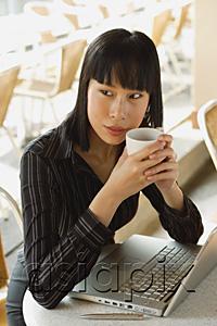 AsiaPix - Businesswoman in cafe with laptop, holding cup