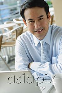 AsiaPix - Businessman in cafe with laptop, smiling at camera