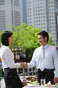 AsiaPix - Businesswoman and businessman at outdoor cafe, shaking hands