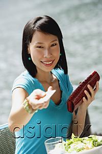AsiaPix - Young woman sitting at riverside cafe, holding credit card towards camera, smiling