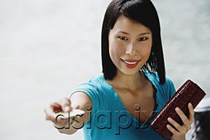 AsiaPix - Young woman  holding credit card towards camera, smiling