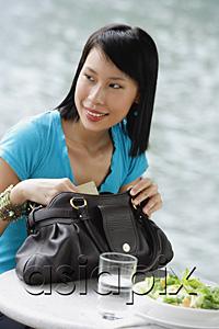 AsiaPix - Young woman sitting at riverside cafe, looking away