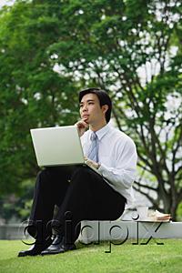 AsiaPix - Businessman sitting in park with laptop