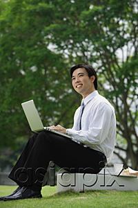 AsiaPix - Businessman sitting in park with laptop