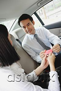 AsiaPix - Two businesspeople in backseat of car, exchanging business cards