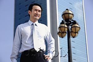 AsiaPix - Businessman standing with hand on hip, looking away