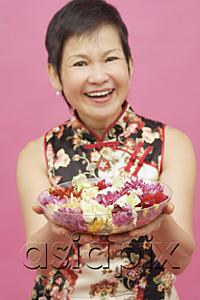AsiaPix - Mature woman holding bowl of flowers