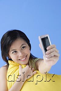 AsiaPix - Young woman hugging pillow, using camera phone