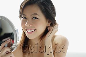 AsiaPix - Young woman holding mirror, smiling at camera