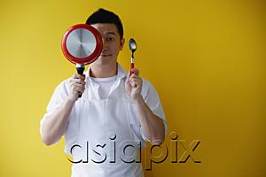 AsiaPix - Man wearing apron, holding saucepan and spoon