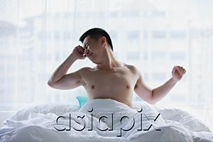 AsiaPix - Man sitting in bed, stretching