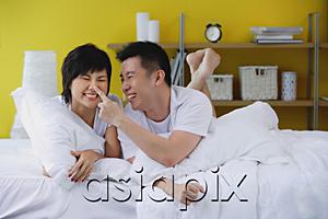 AsiaPix - Couple lying on bed, man touching woman's nose