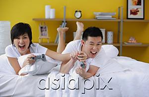 AsiaPix - Couple lying on bed, playing video game