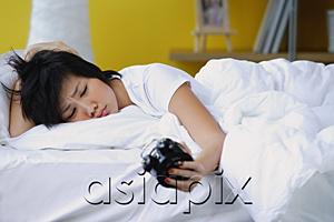 AsiaPix - Woman in bed, looking at alarm clock, frowning