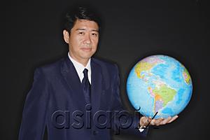 AsiaPix - Businessman holding globe, looking at camera