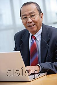 AsiaPix - Businessman with laptop, smiling at camera