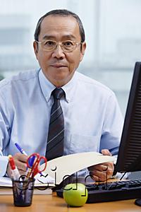 AsiaPix - Businessman sitting at his desk, looking at camera