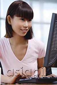 AsiaPix - Young woman sitting in front of computer