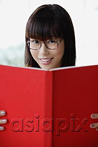 AsiaPix - Young woman smiling at camera, holding book