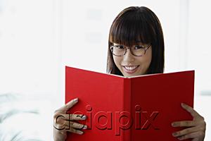 AsiaPix - Young woman holding book, smiling at camera
