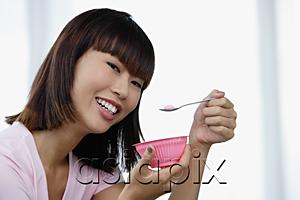 AsiaPix - Young woman eating from pink bowl