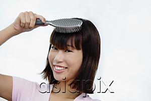 AsiaPix - Young woman brushing her hair, smiling at camera