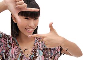 AsiaPix - Young woman smiling at camera, making finger frame