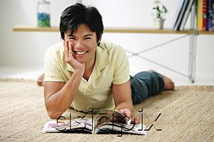 AsiaPix - Man lying on floor, hand on chin, smiling at camera