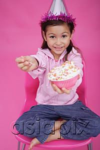AsiaPix - Girl with party hat, sitting on chair, holding bowl of cake towards camera