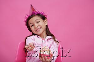 AsiaPix - Girl wearing party hat, holding bowl of cake towards camera