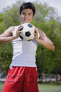 AsiaPix - Young man holding soccer ball, looking at camera