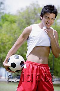 AsiaPix - Young man with soccer ball, wiping chin with T shirt