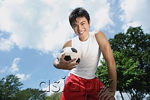 AsiaPix - Young man holding soccer ball, smiling at camera