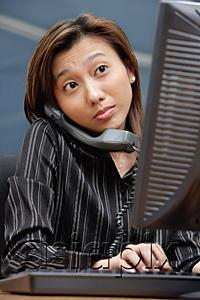AsiaPix - Female executive at desk, using computer and telephone
