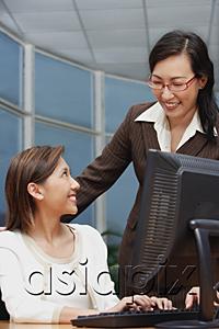 AsiaPix - Female executive at computer, smiling at woman standing next to her