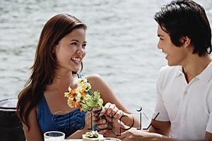 AsiaPix - Couple sitting at outdoor cafe, man handing a woman flowers