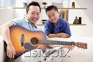 AsiaPix - Father and son smiling at camera, father holding guitar