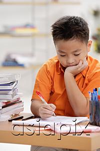 AsiaPix - Boy sitting at desk, doing homework