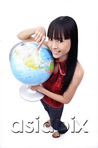 AsiaPix - Young woman holding and pointing at globe, smiling at camera