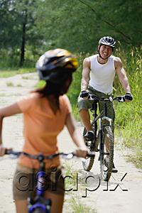 AsiaPix - Couple cycling, woman in foreground turning to look at man in the background