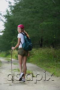 AsiaPix - Woman on hiking trail, looking over shoulder at camera
