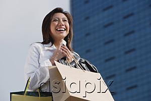 AsiaPix - Woman carrying shopping bags, holding mobile phone, smiling
