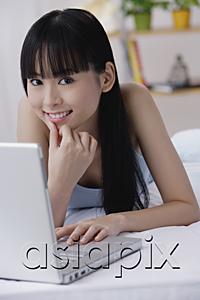 AsiaPix - Young woman with laptop, hand on chin, smiling at camera
